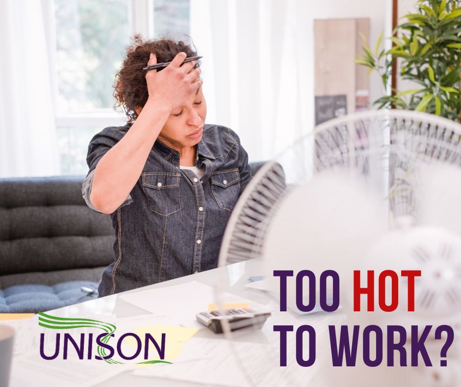 A worker struggling to work in an officer with a fan in the foreground
